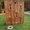 Rustic wooden ring toss wall garden game hire, popular outdoor wedding and party entertainment.